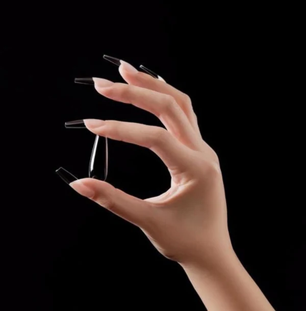 Una sola uña con extensión de tip de gel lechoso y esmalte nude sobre fondo de lino claro difuminado.